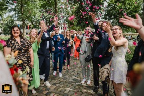   Wedding guests outside at Rittergut Störmede in Geseke, Germany, joyfully shower the newlyweds with flower petals, marking the start of their celebration during the congratulatory moment.